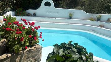 Una piscina con una pared blanca y un elemento decorativo de roca.