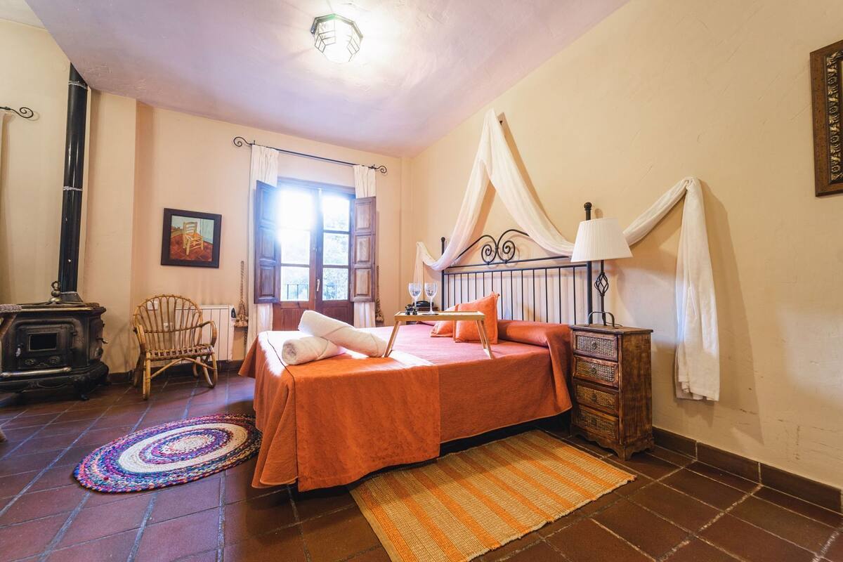 Ein Schlafzimmer mit Bett, Stuhl, Holzschrank, Herd und Fenster.