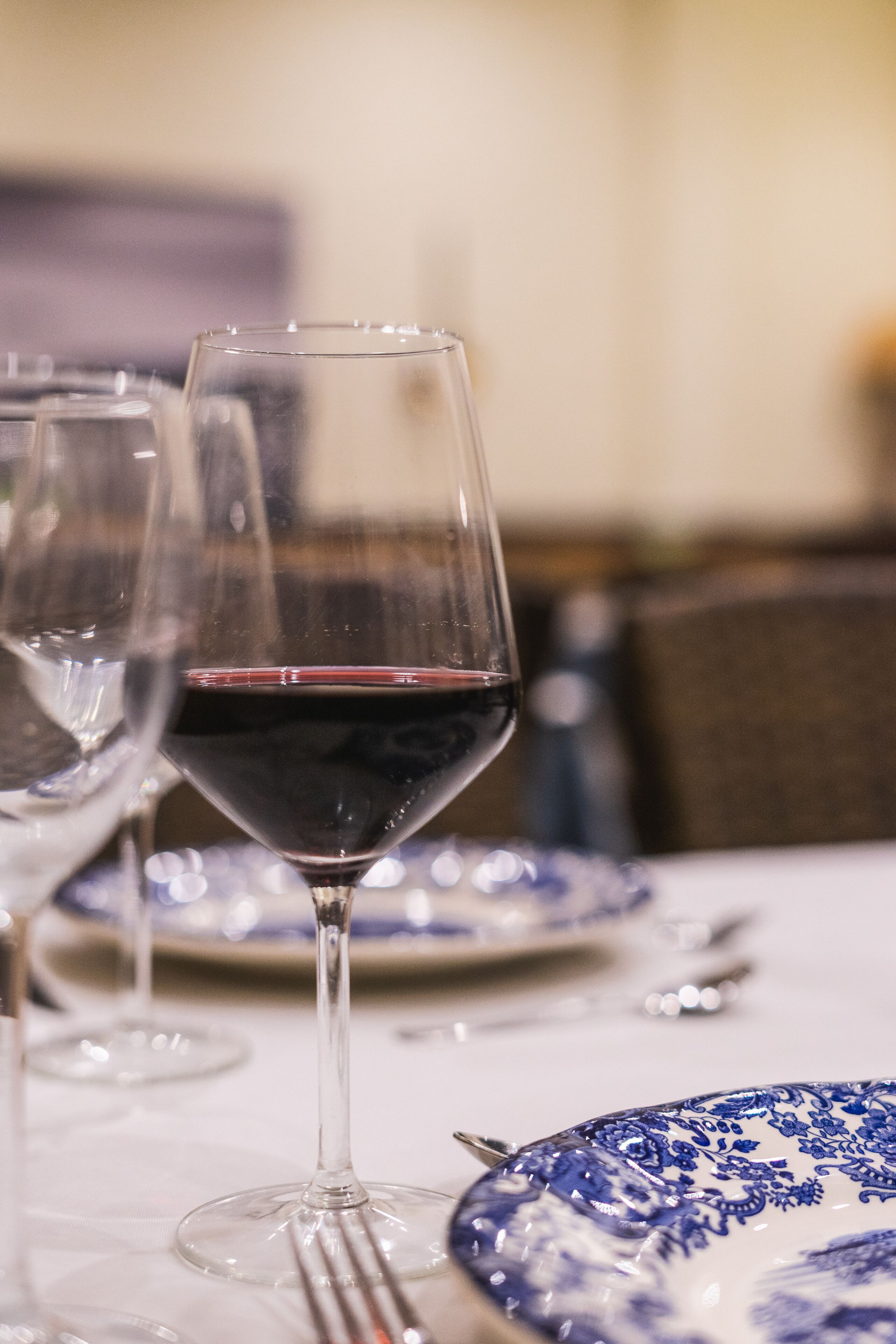 Una mesa de comedor con copas de vino y platos de diseño azul y blanco.