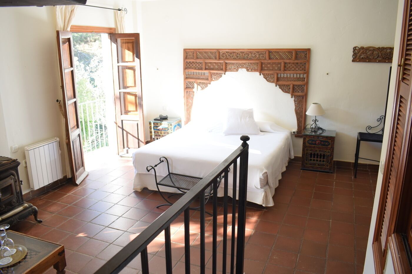 A bedroom with a bed, a nightstand, a lamp, a radiator, and a window with curtains.
