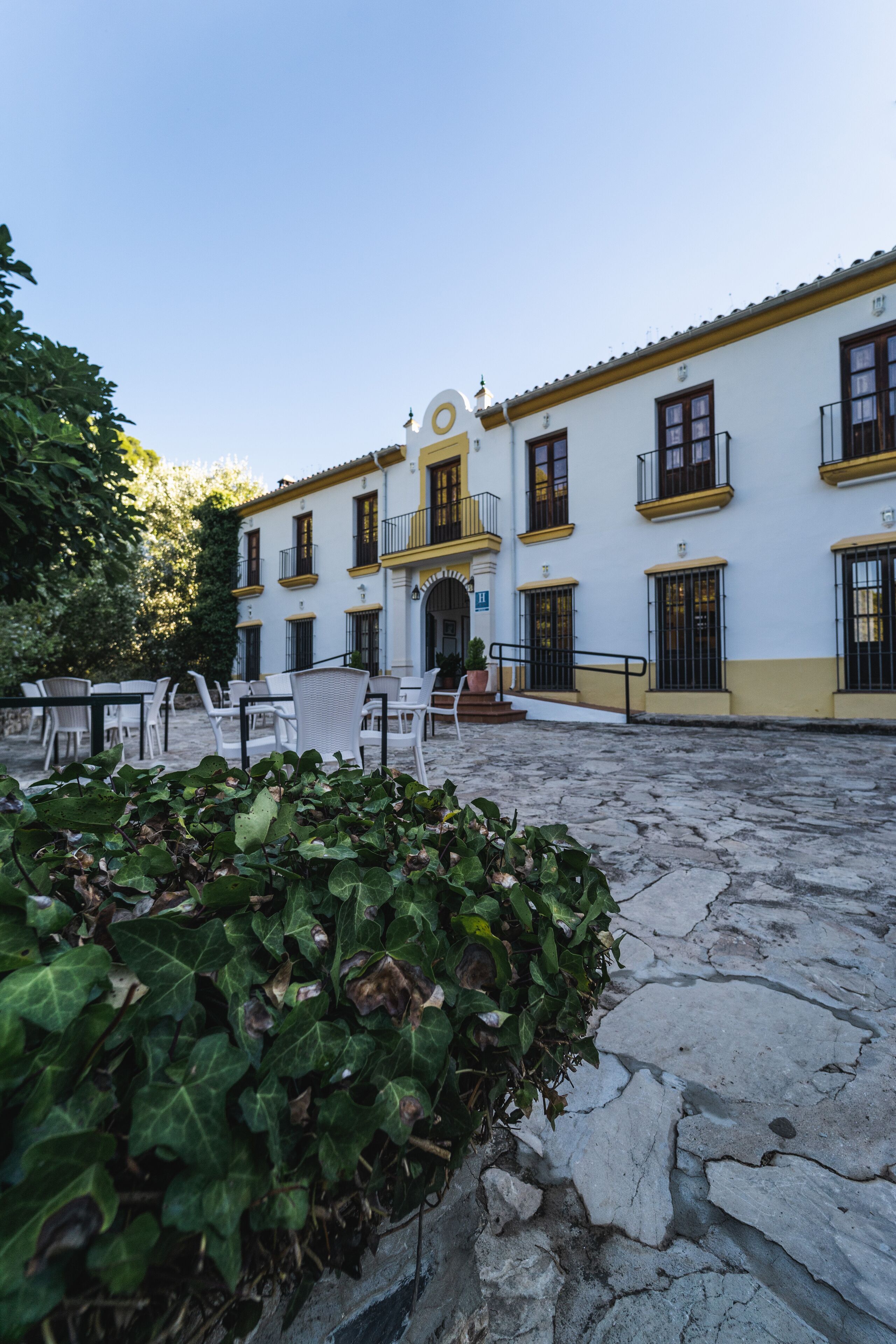Un patio con edificios blancos, mobiliario exterior y suelo de piedra.