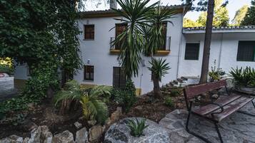 Un edificio con fachada blanca, varias ventanas y un banco de piedra en primer plano.