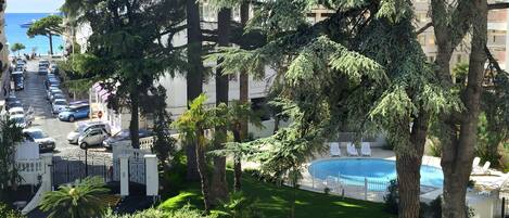 Un resort con piscina, vegetación exuberante y vista al mar.