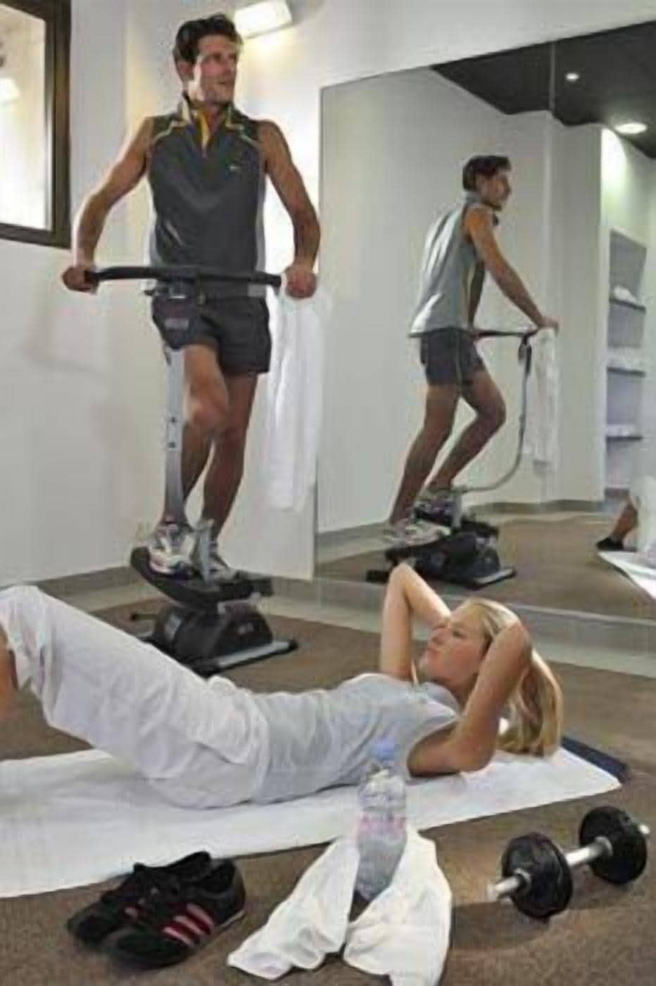 A gym with exercise equipment and a person lying on a mat.