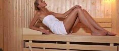 A sauna with wooden benches and a person lying on one.