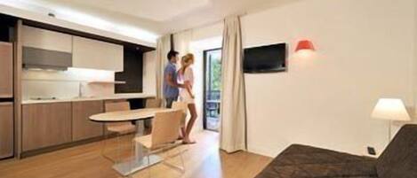 Una cocina moderna con comedor, sofá y televisor.