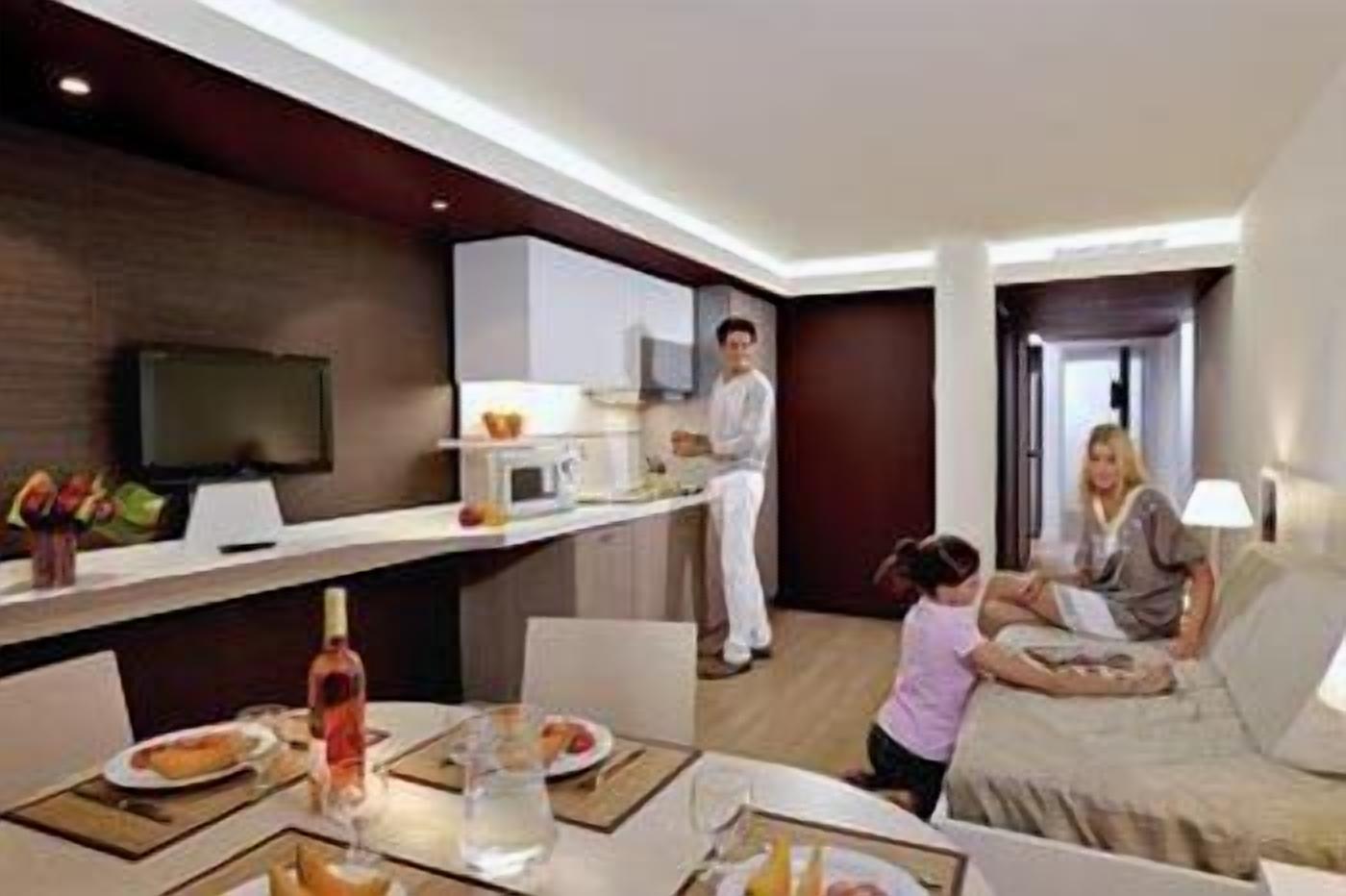 Une chambre d’hôtel moderne dotée d’un coin repas, d’une cuisine et d’un espace de vie.