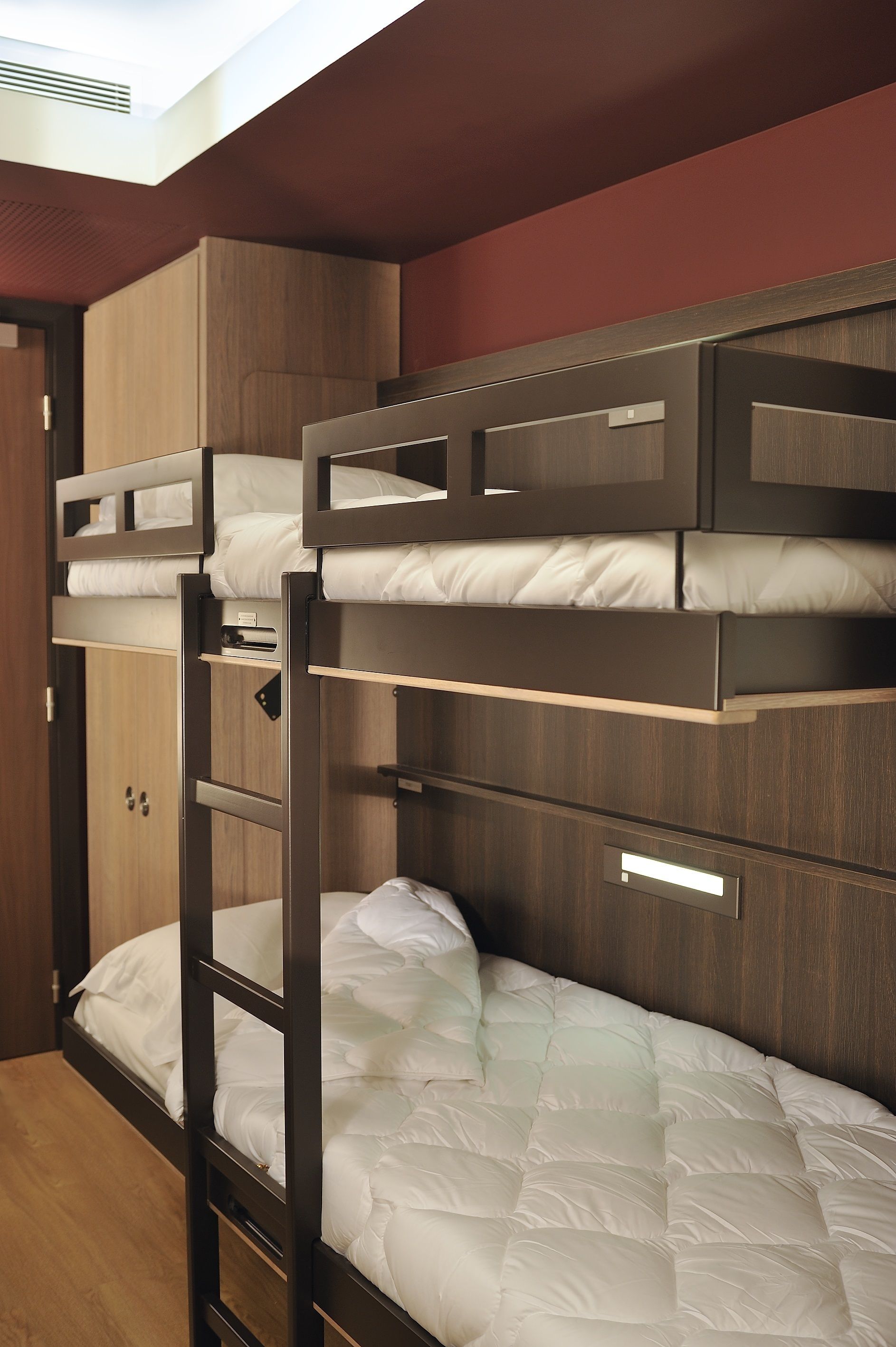 A bunk bed room with wooden walls and a wardrobe.