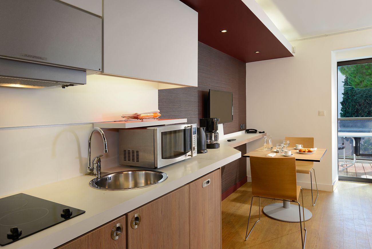 A modern kitchen with a microwave, sink, and a dining area with a table and chairs.