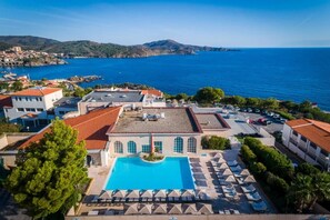 A hotel with a rooftop pool, lounge chairs, and a view of the sea. - Côté Thalasso (Banyuls-sur-Mer)