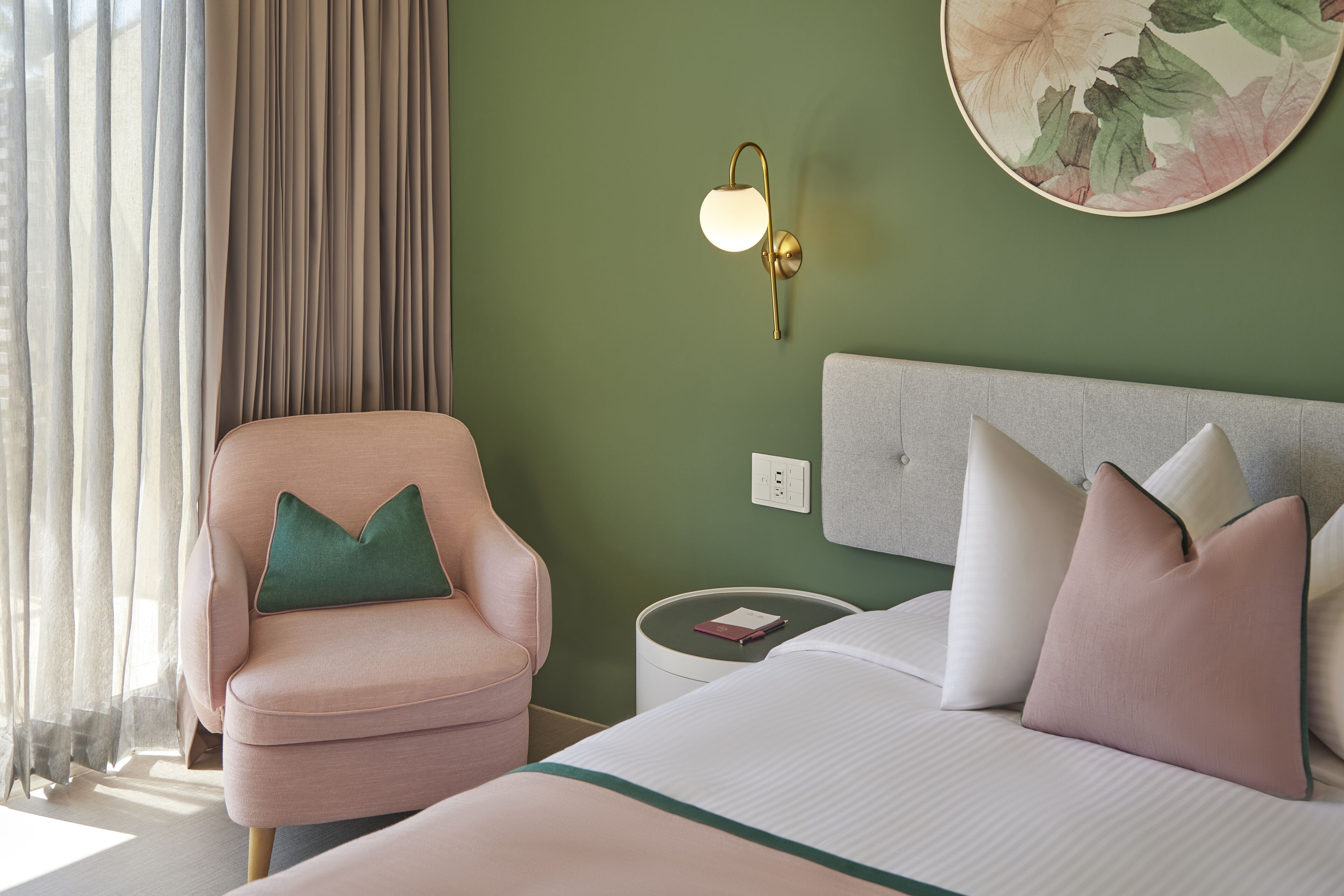 Una habitación de hotel con cama, una silla, una mesita de noche y una lámpara fijada a la pared.