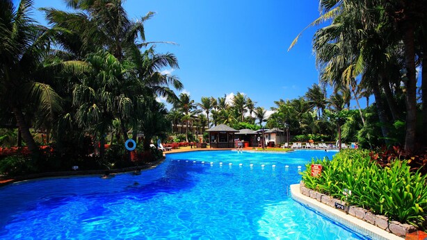 A large swimming pool surrounded by palm trees and lounge chairs. - Caesar Park Kenting (Hengchun)