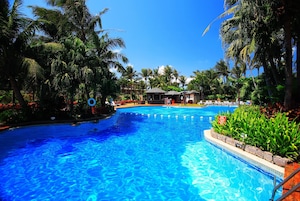 Una piscina al aire libre, sombrillas, sillones reclinables de piscina