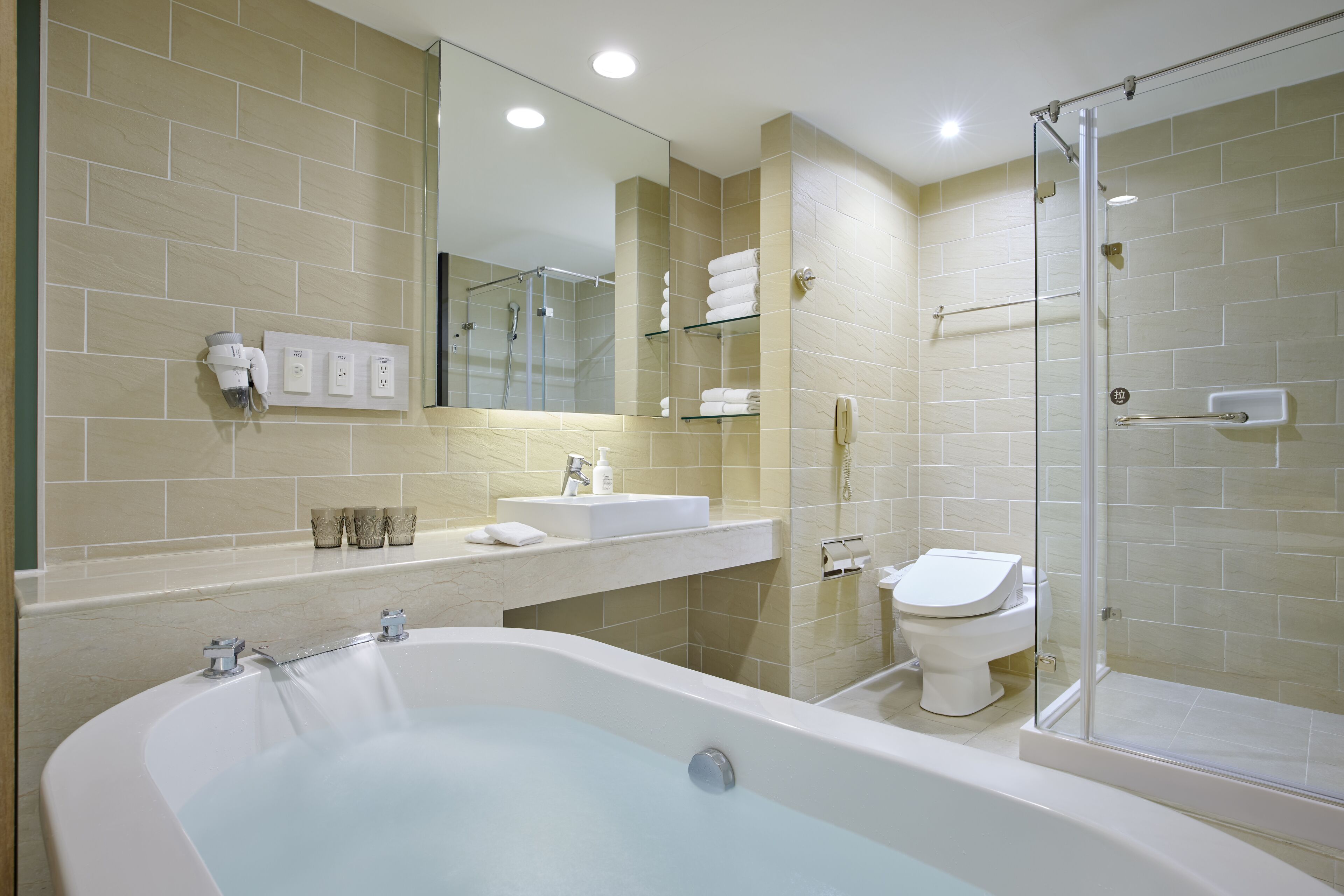 A modern bathroom with a large bathtub, a glass-enclosed shower, and a toilet.