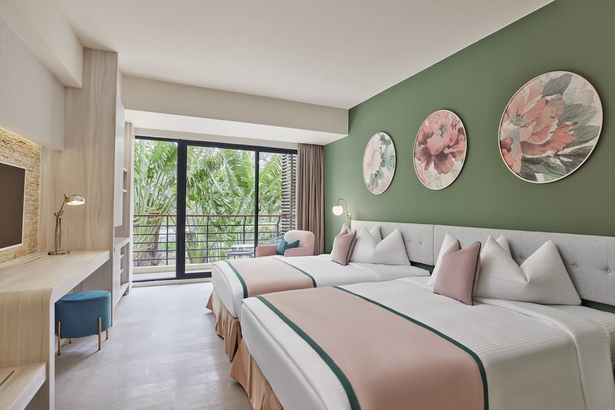 A hotel room with two beds, a desk, and a large window with a view of greenery.