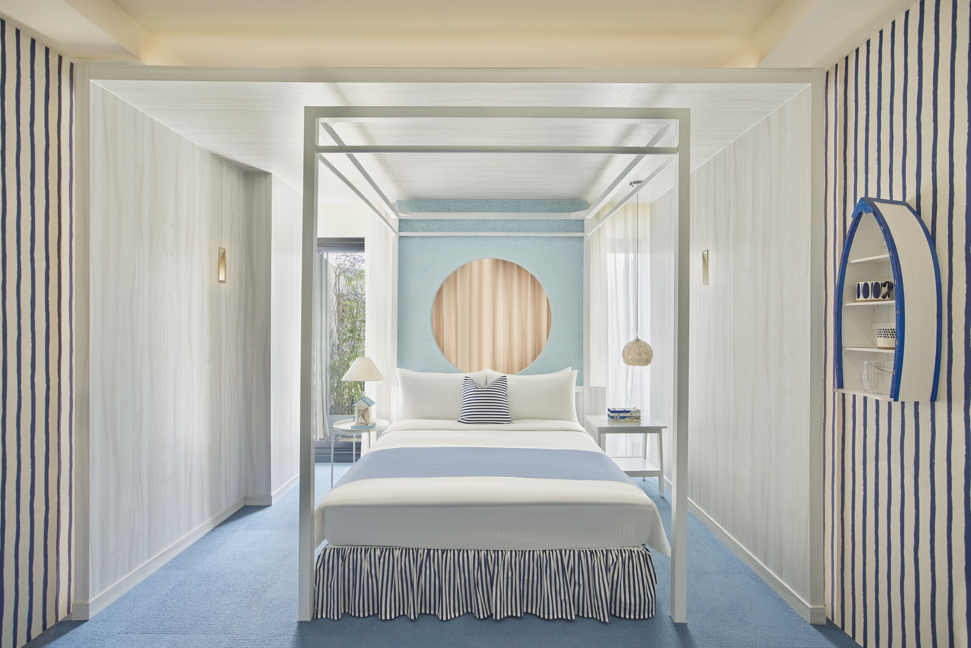 A modern bedroom with a canopy bed, a circular wall feature, and striped decor.