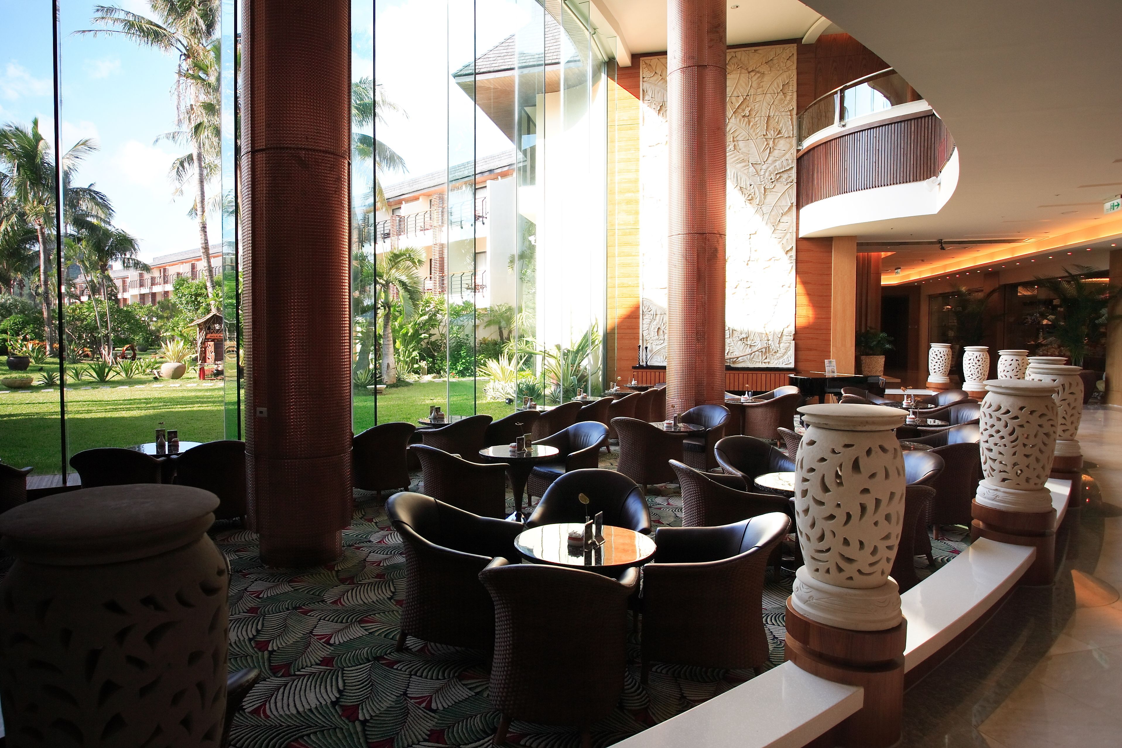 A hotel lobby with outdoor seating, large windows, and a view of a landscaped garden.