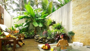 A tropical spa setting with a hot tub, wooden deck, and lush greenery. - Caesar Park Kenting (Hengchun)