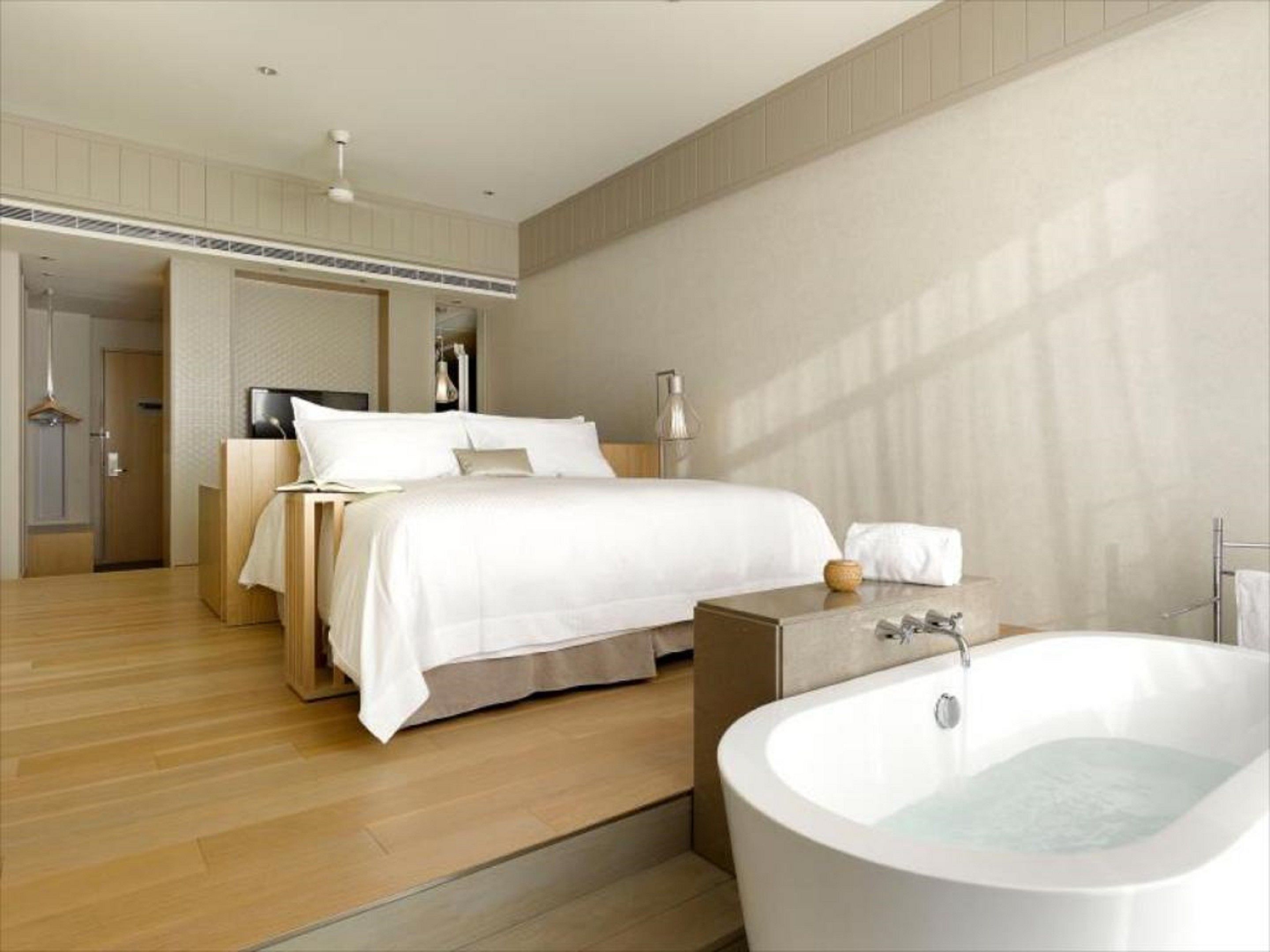 Una habitación de hotel moderna con una cama grande, un baño separado con bañera y un vestidor.