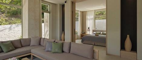 A modern hotel room with a large sofa, a coffee table, and a bed.