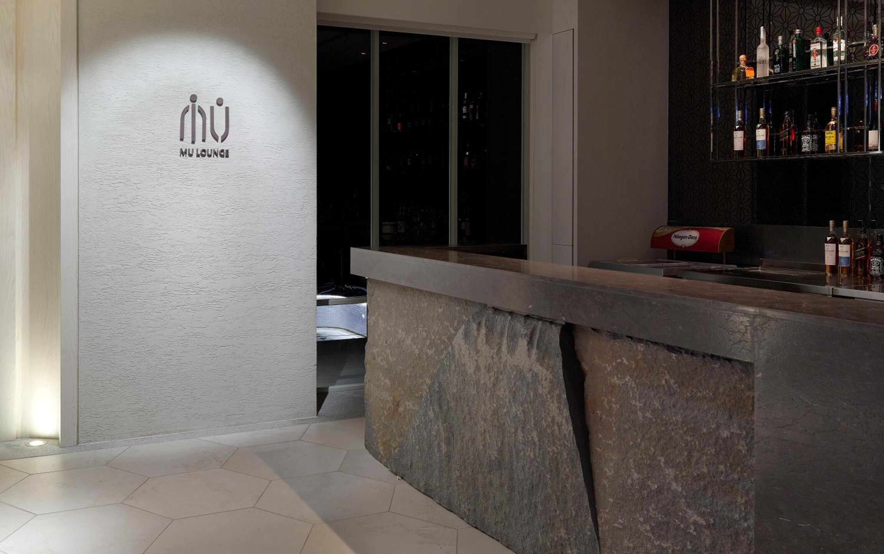 A bar area with a sign reading "MU Lounge" and a bar stocked with various bottles.