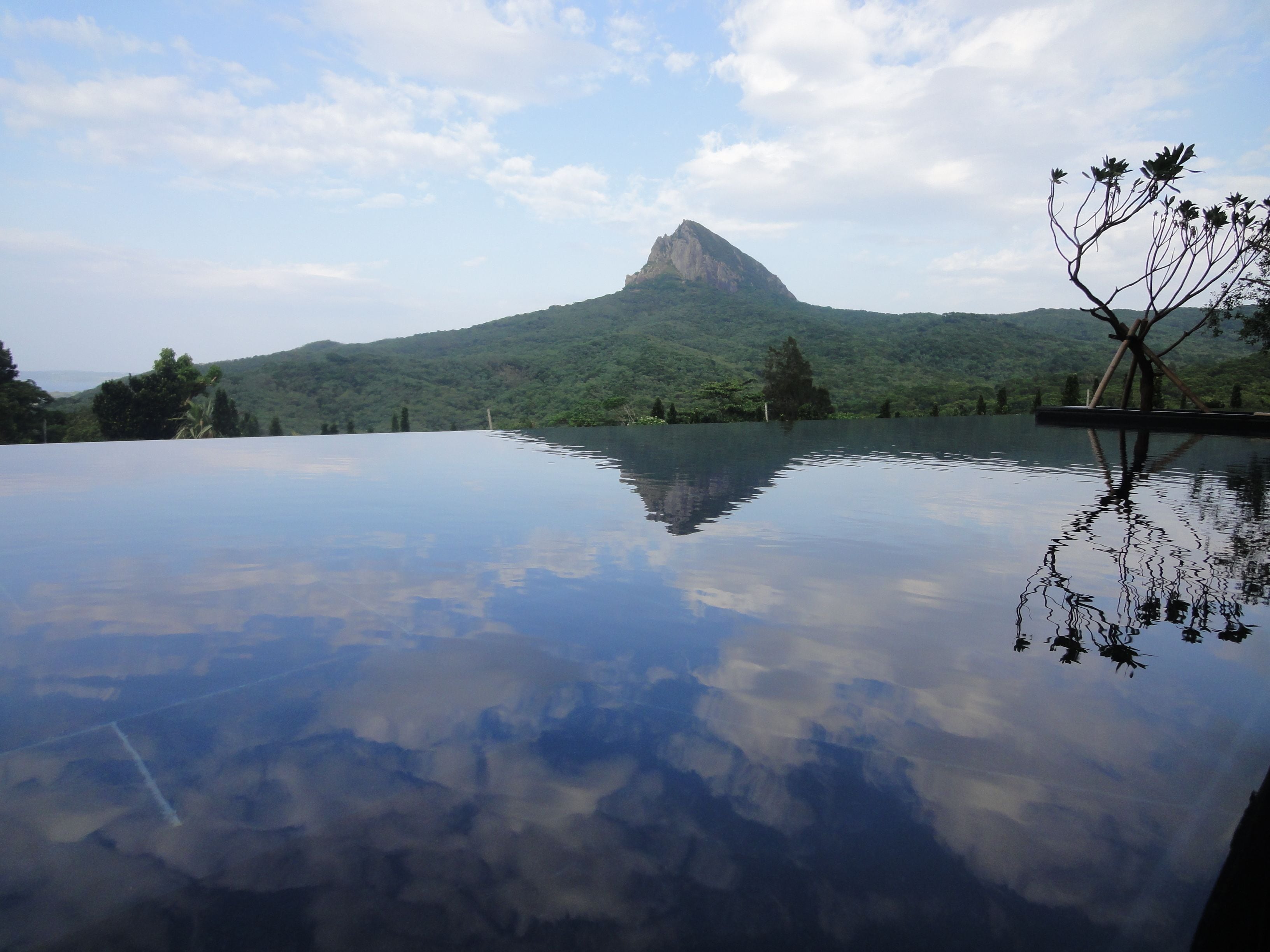 Vista despejada de una montaña reflejada en el agua, rodeada de vegetación.