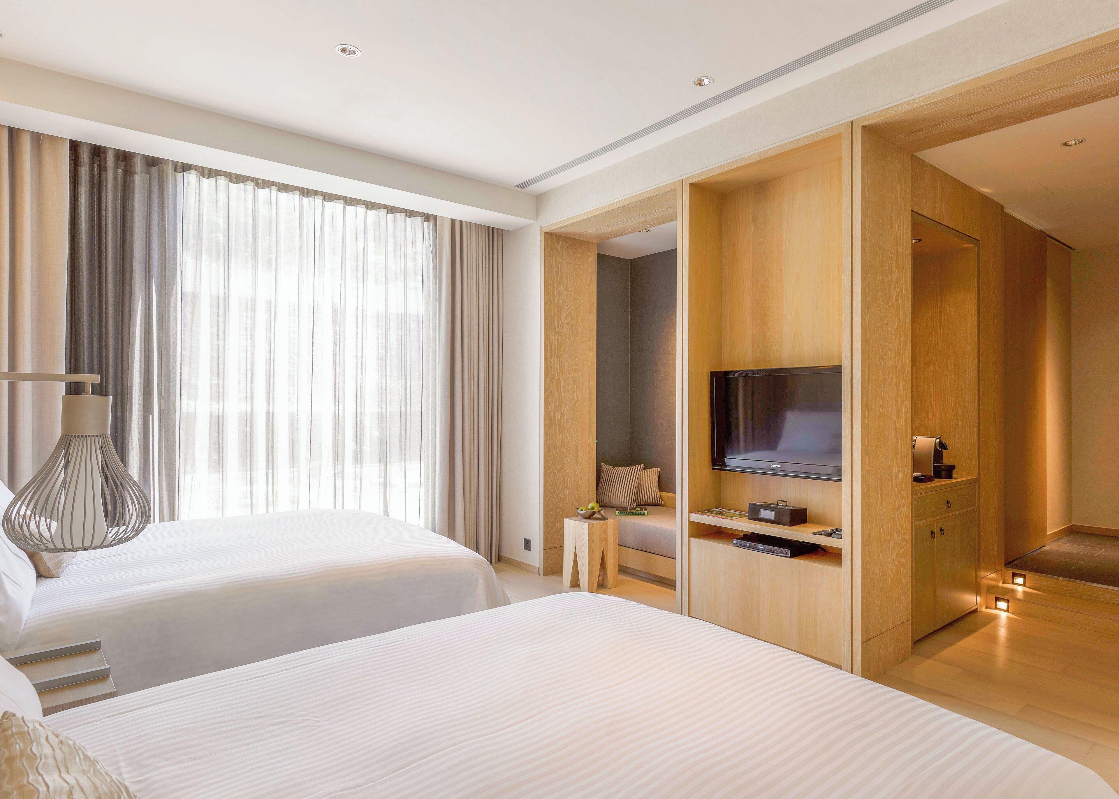 A hotel room with two beds, a TV, and a wooden wardrobe.