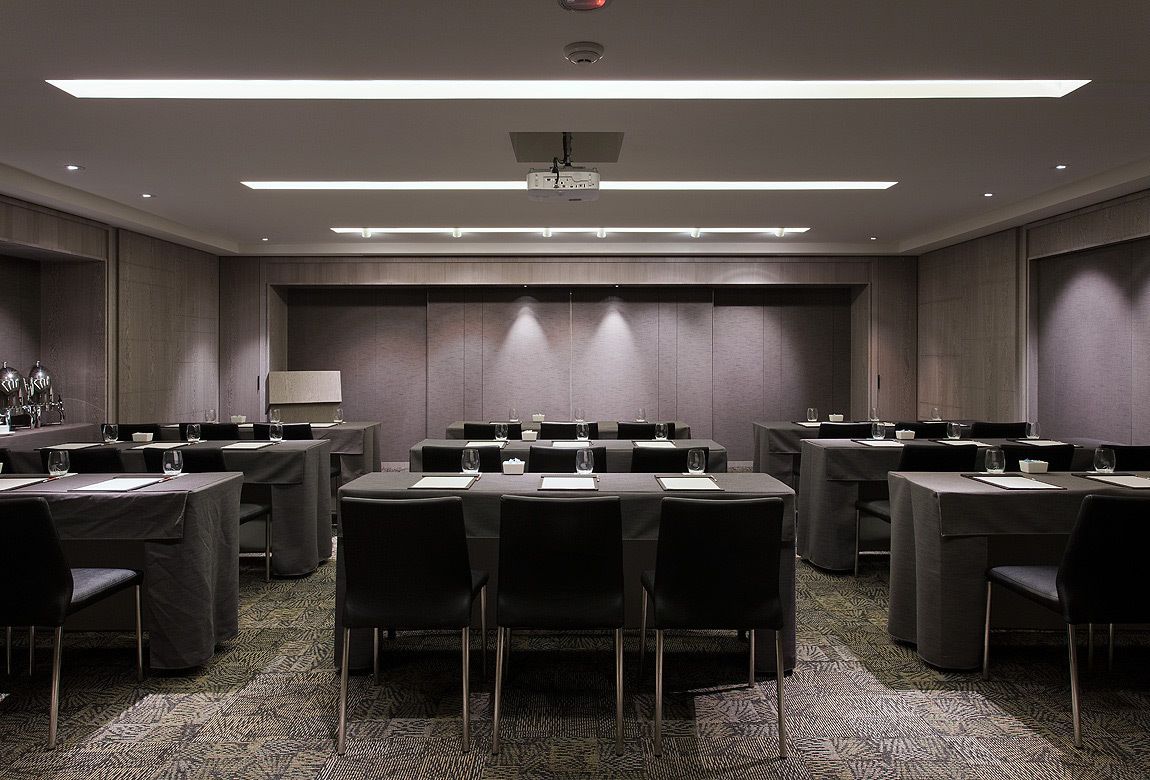 A conference room with multiple tables and chairs, equipped with projectors and a large screen.