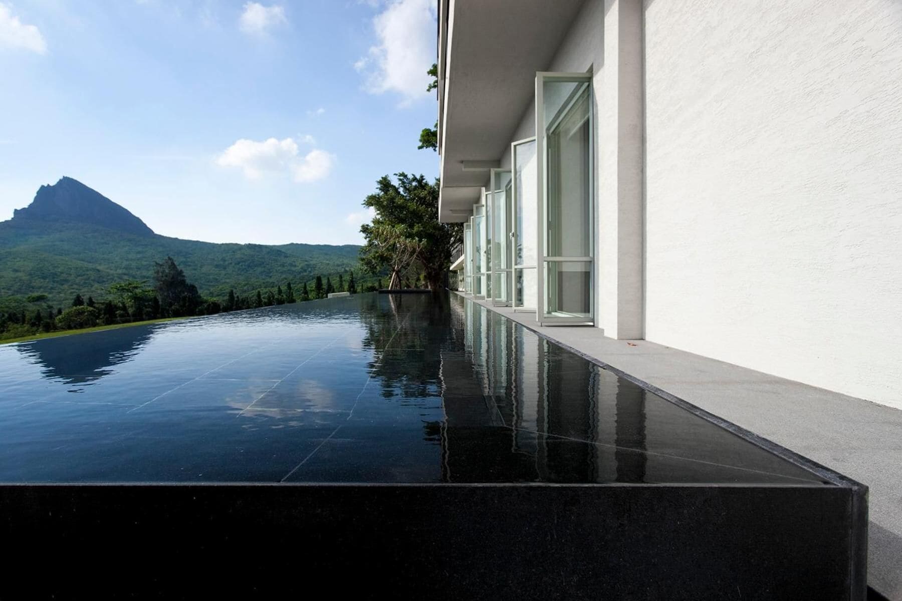 A modern building with a reflective pool and a mountain view.