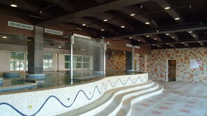 A swimming pool with a wavy design on the edge, surrounded by a tiled floor and walls. - Fullon Resort Kending (Hengchun)