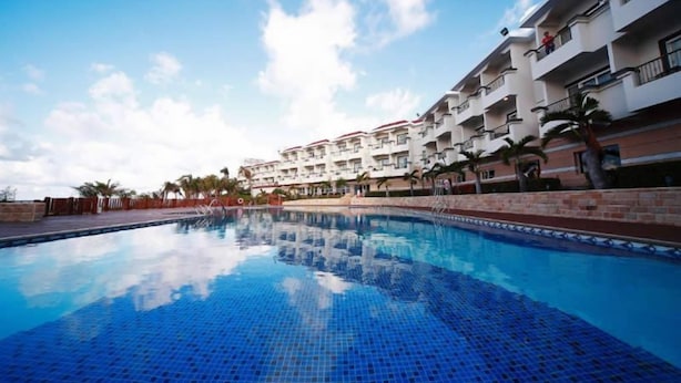 A hotel with a swimming pool, multiple balconies, and palm trees. - Fullon Resort Kending (Hengchun)