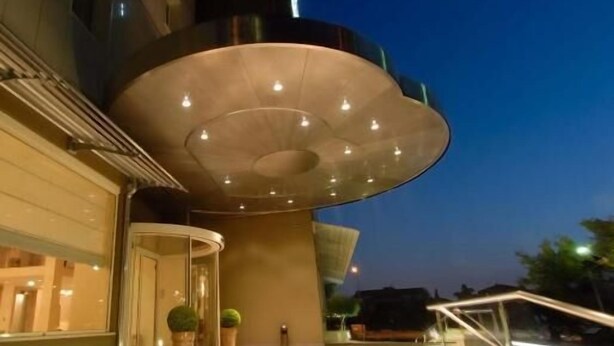 Un bâtiment moderne doté d’une entrée incurvée et d’un grand auvent illuminé.
