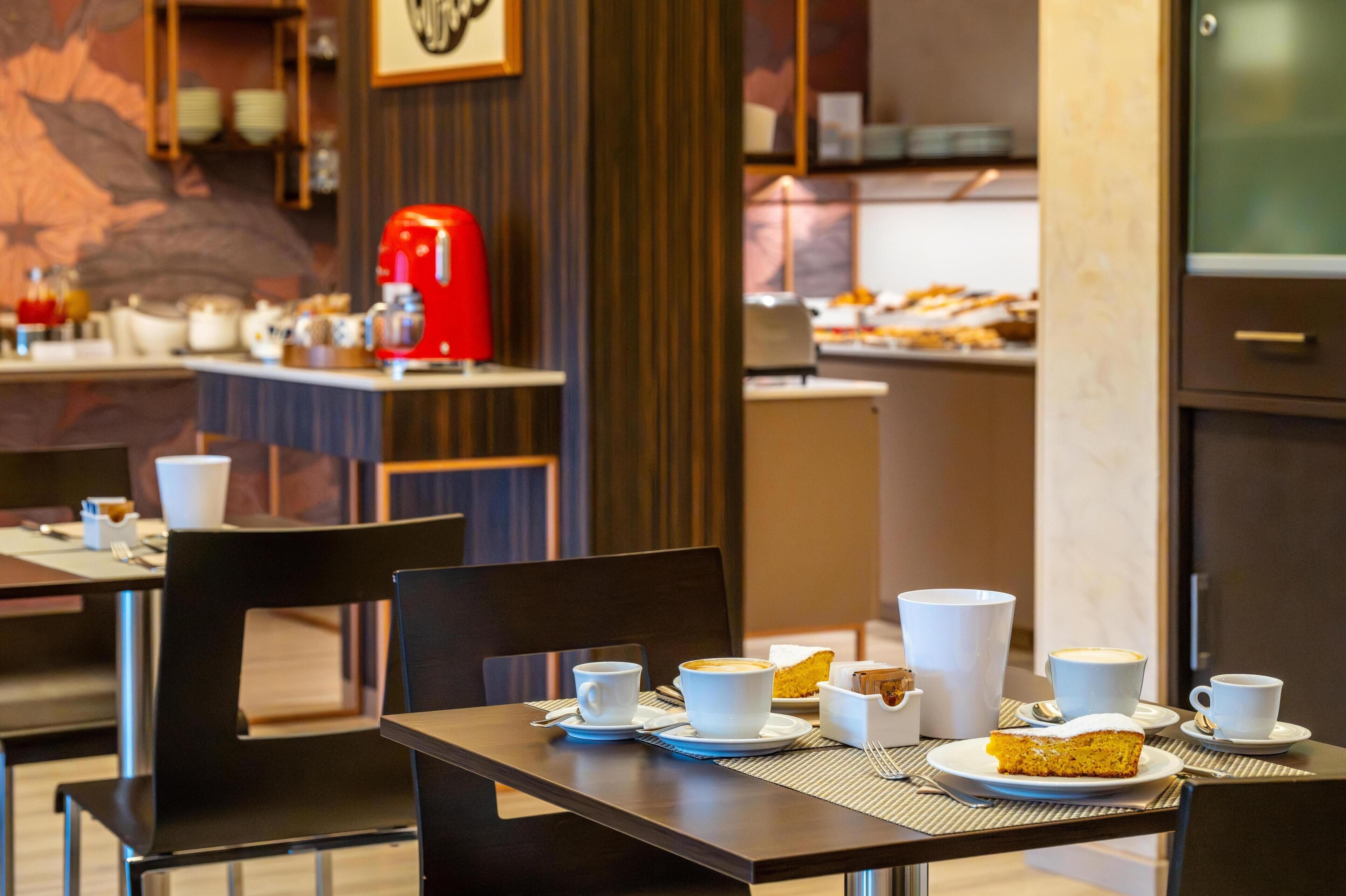 A dining area with tables set for breakfast, including coffee and pastries.
