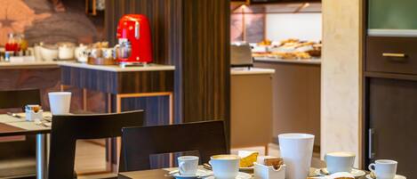 A dining area with tables set for breakfast, including coffee and pastries.