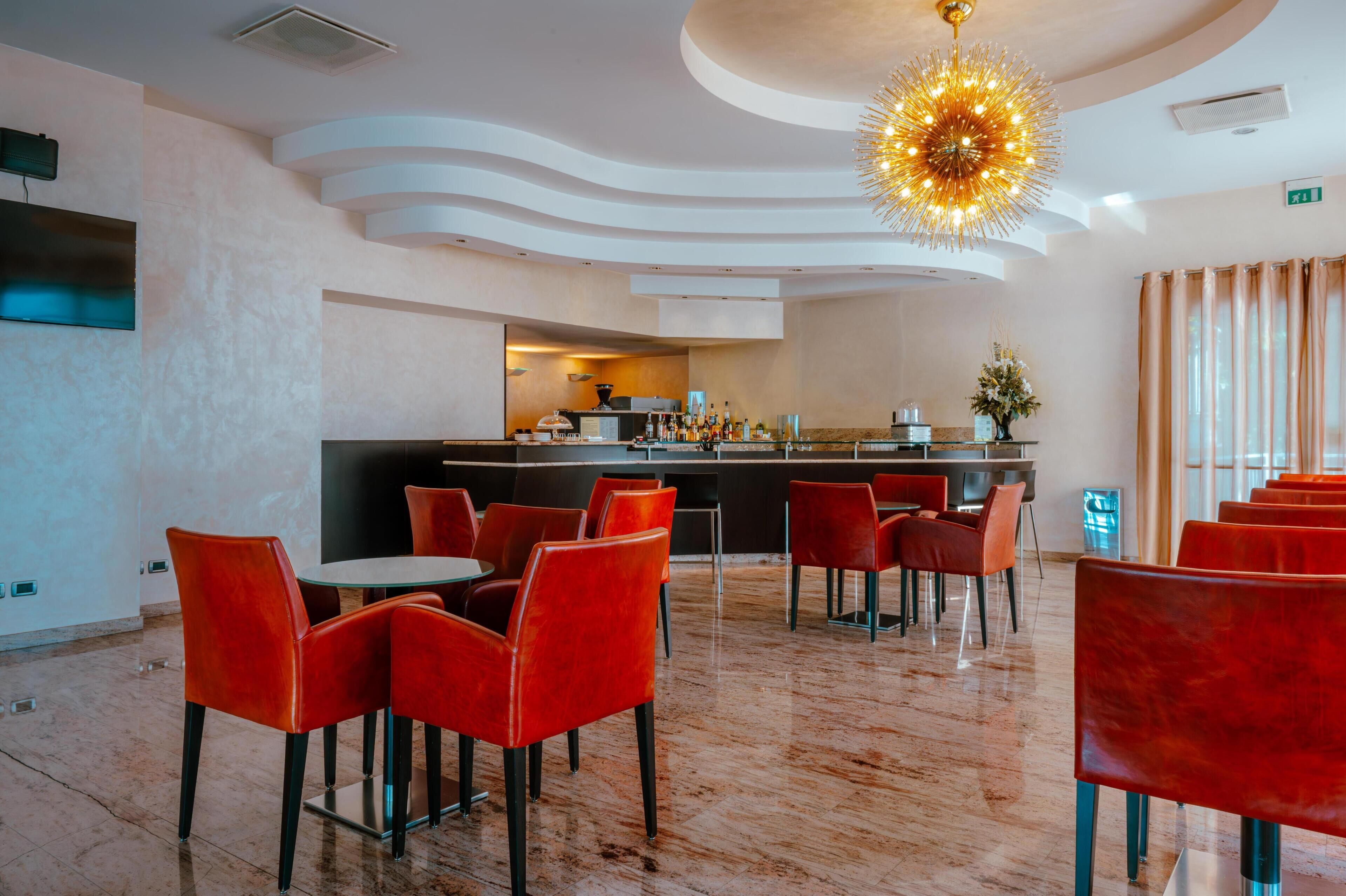 A modern restaurant with red chairs, a bar area, and a unique ceiling design.