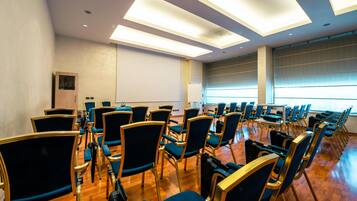 A conference room with rows of chairs, a whiteboard, and a projector screen.
