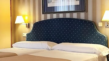 A hotel room with a large bed, two bedside lamps, and a framed picture on the wall.