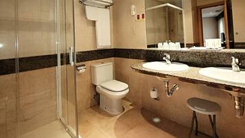 A modern bathroom with a glass-enclosed shower, a toilet, a sink with a vanity, and a large mirror.