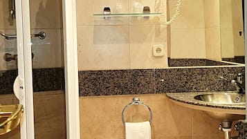A bathroom with a glass shower enclosure, a sink with a granite countertop, a toilet, and a mirror above the sink.