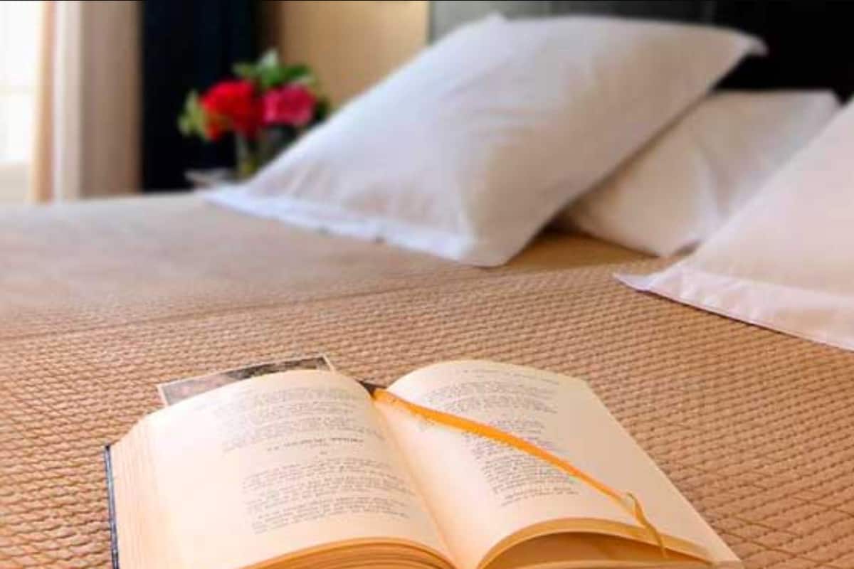 Una cama bien hecha con una almohada blanca y un libro encima.
