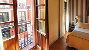 A hotel room with a balcony, a bed, and a view of the street. - Hotel Imperial (Valladolid)