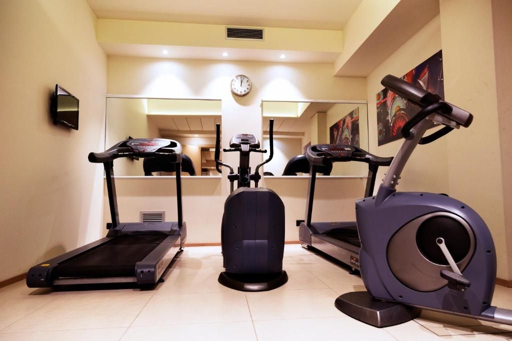 Sala de ginástica com esteiras, elíptico e bicicleta ergométrica.