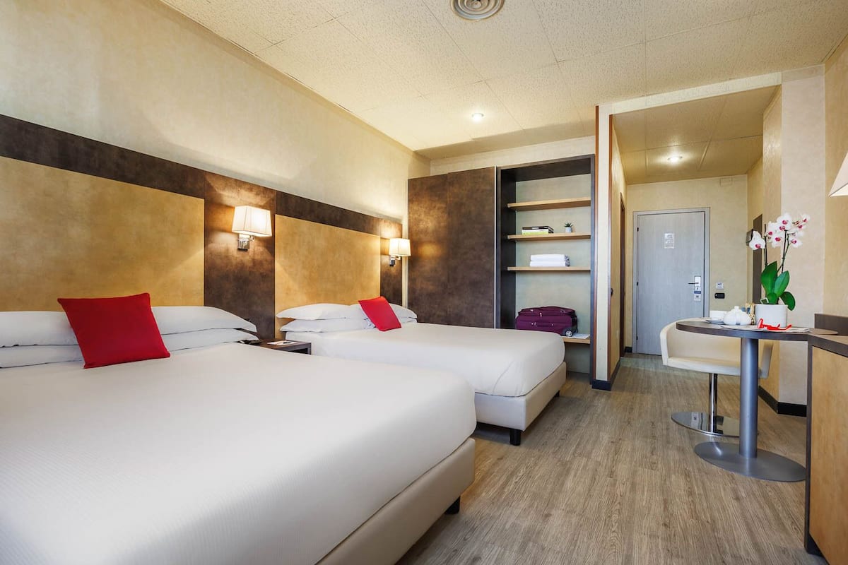 Una habitación de hotel con dos camas, un escritorio y un minibar.