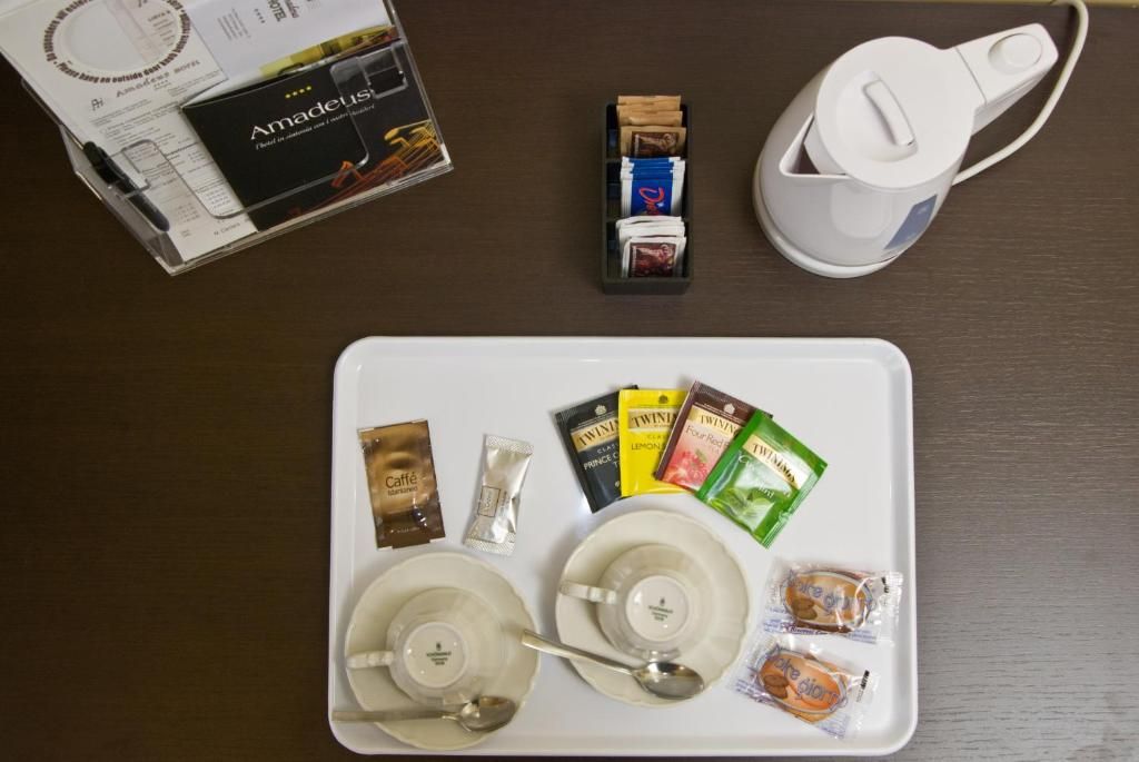 A tray with a coffee maker, tea bags, and snacks on a table.