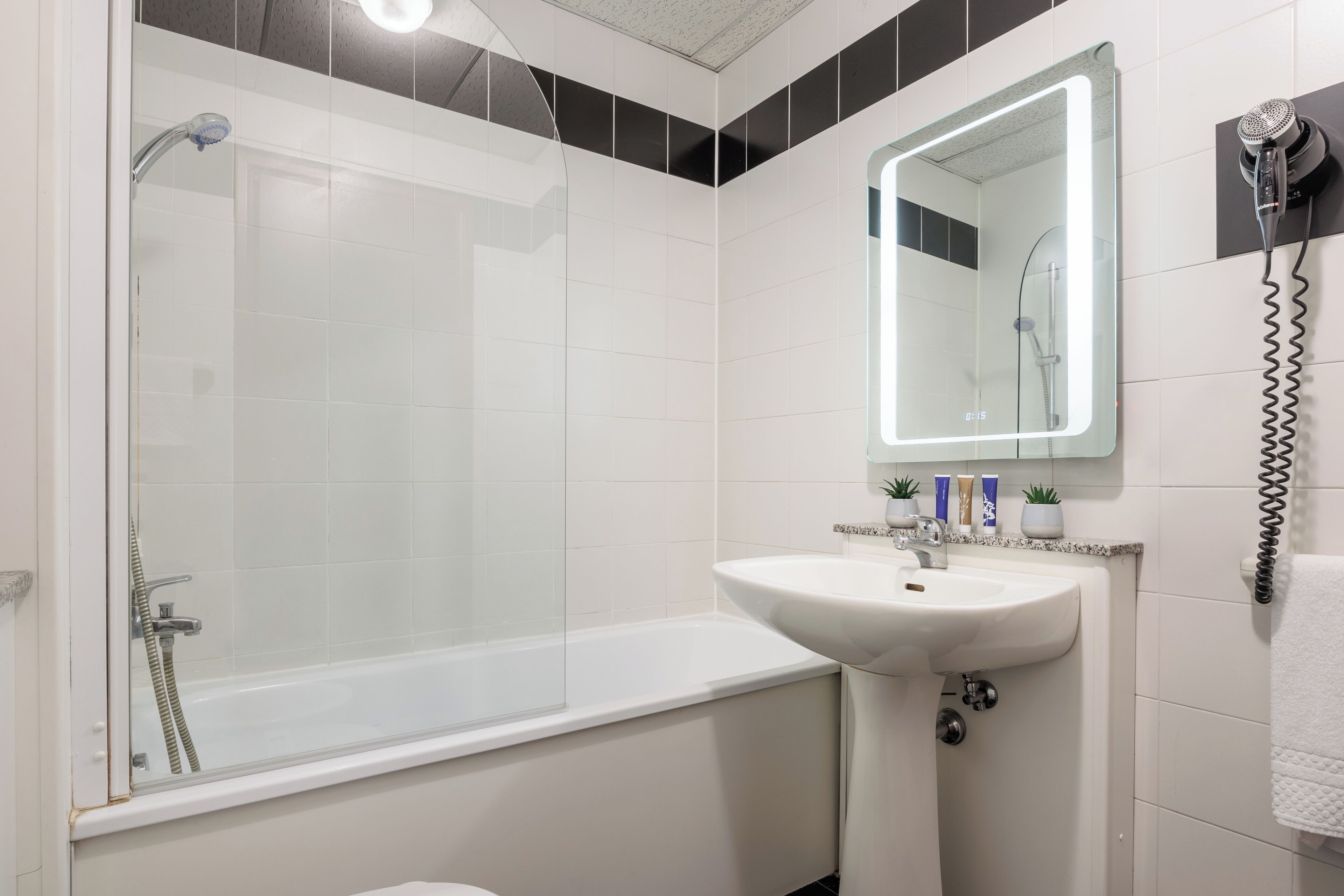 A modern bathroom with a glass-enclosed shower, a white sink, and a mirror above it.