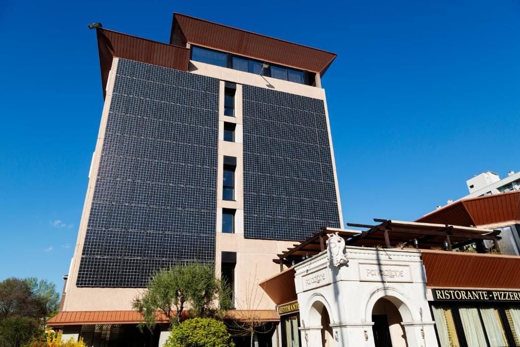 Un edificio alto de diseño moderno, con un amplio frente de vidrio y un restaurante en la planta baja.