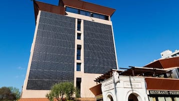 Un edificio alto de diseño moderno, con un amplio frente de vidrio y un restaurante en la planta baja.