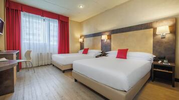 Ein Hotelzimmer mit zwei Betten, einem Schreibtisch, einem Stuhl und einem Fernseher.