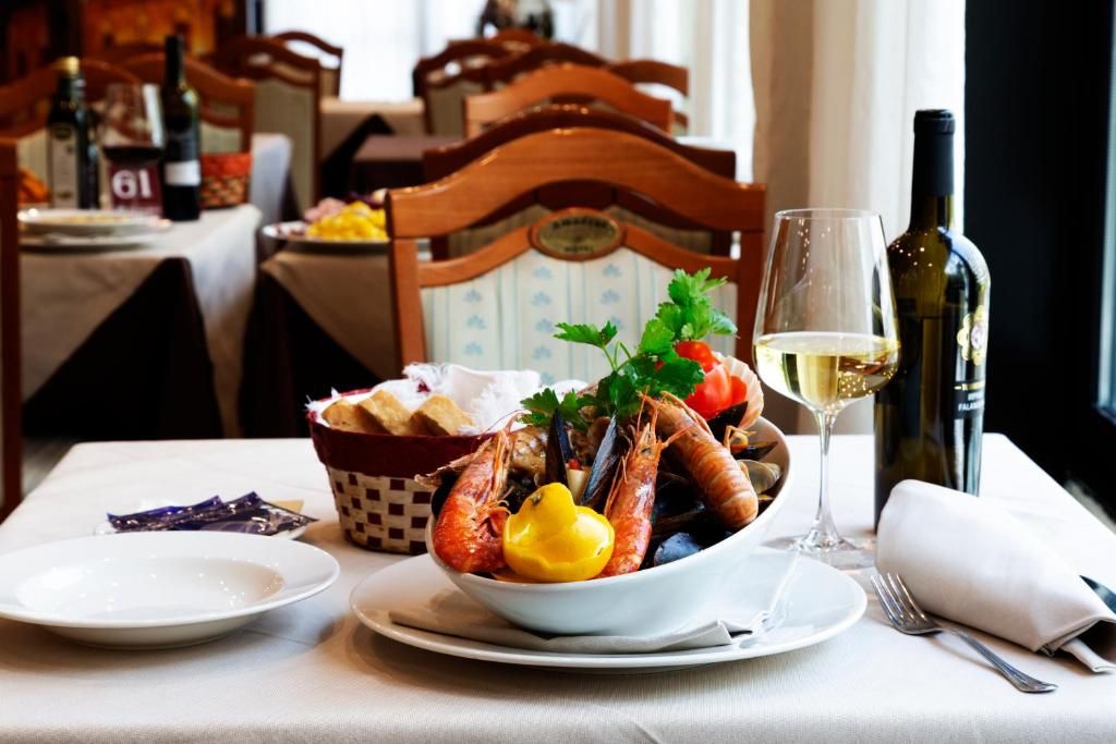 A dining table with a bowl of seafood, a glass of white wine, and a bottle of wine.