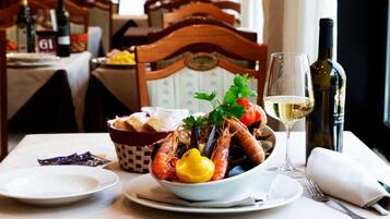 A dining table with a bowl of seafood, a glass of white wine, and a bottle of wine.